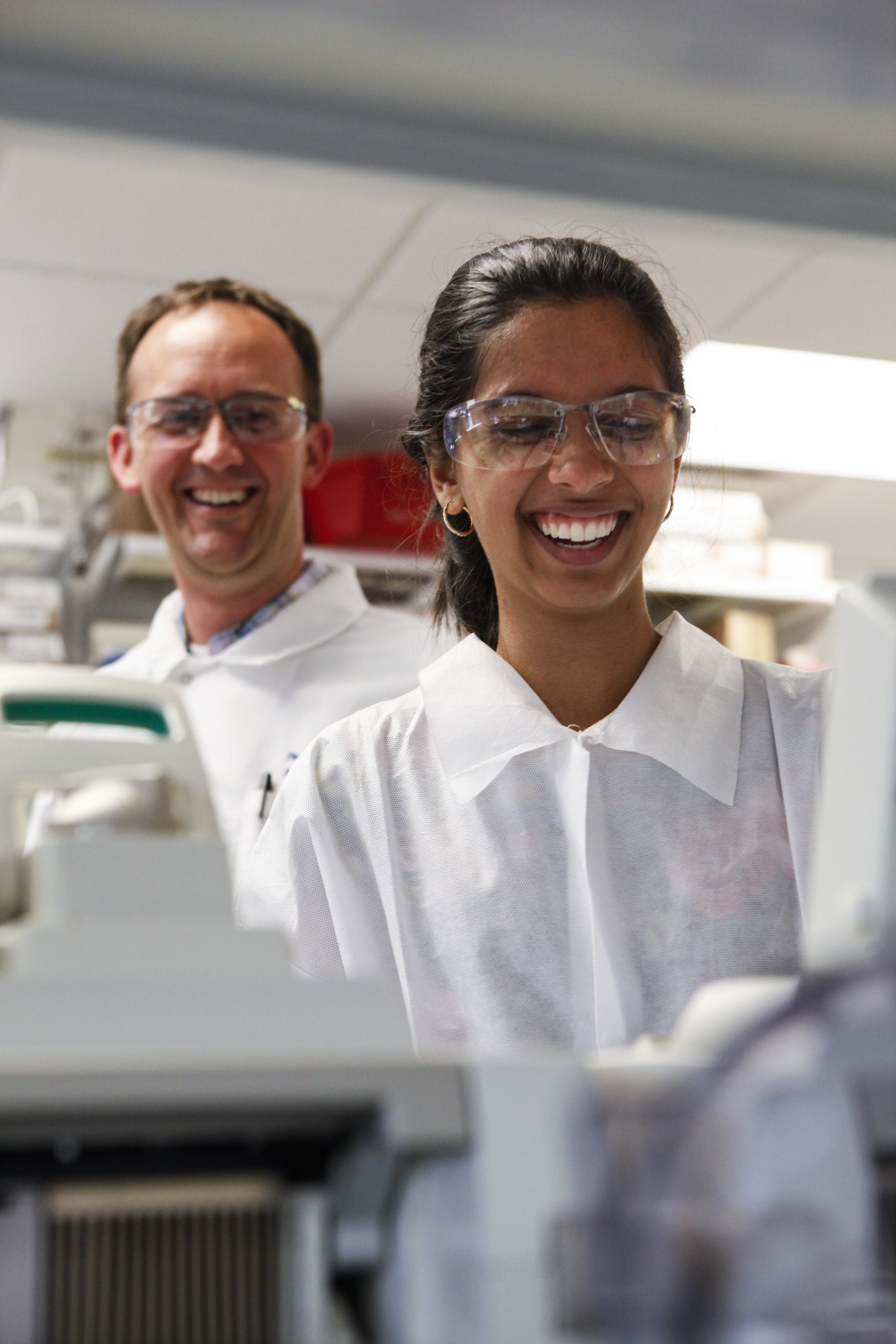 A summer student and faculty enjoy a laugh during their lab work.